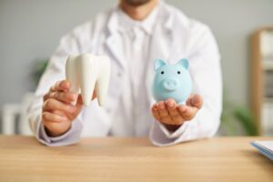 Dentist holding piggy bank and tooth model